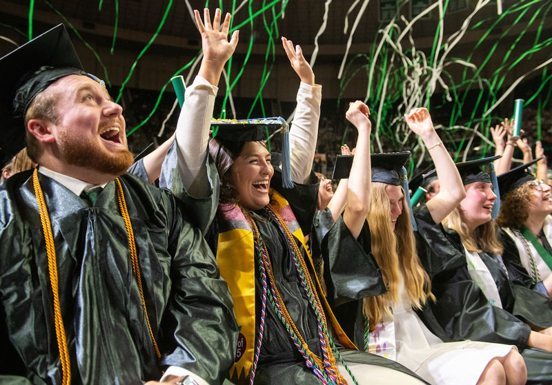 Students celebrate during Commencement ceremony, wearing their caps and gowns.