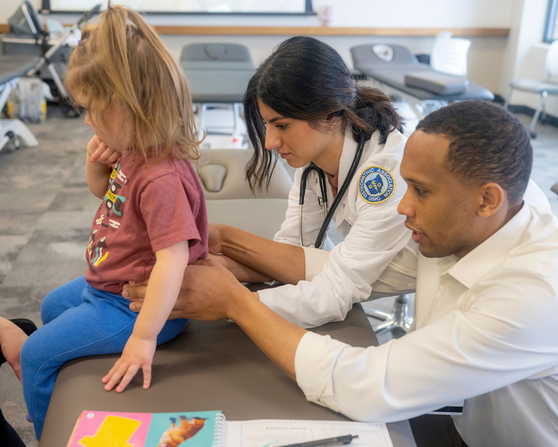 Two medical students perform an examination on a child.