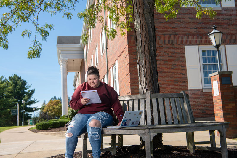 A student studies outside in front of a brick building on OHIO’s Eastern campus.