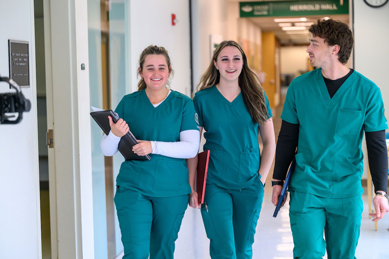 Three nursing students walk down a hallway while wearing scrubs at OHIO’s Zanesville campus.