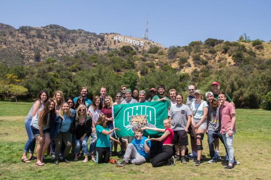 Ohio University students pose with an OHIO flag in front of the Hollywood sign